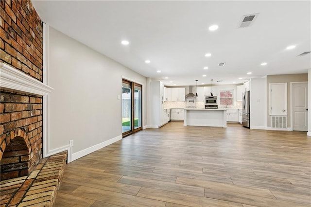 1424 Pecan Ave, Metairie, LA 70001 - unfurnished living room with a brick fireplace, recessed lighting, and light wood-style flooring
