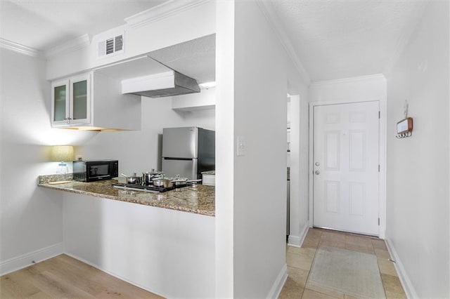 3805 Houma Blvd Unit A243, Metairie, LA 70006 - kitchen with freestanding refrigerator, black microwave, glass insert cabinets, ornamental molding, and stone counters