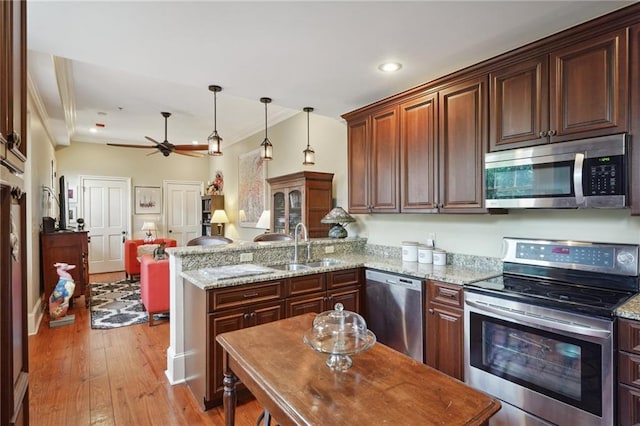 1225 Bourbon St Unit F, New Orleans, LA 70116 - kitchen with stainless steel appliances, a peninsula, crown molding, light wood-style flooring, and light stone countertops