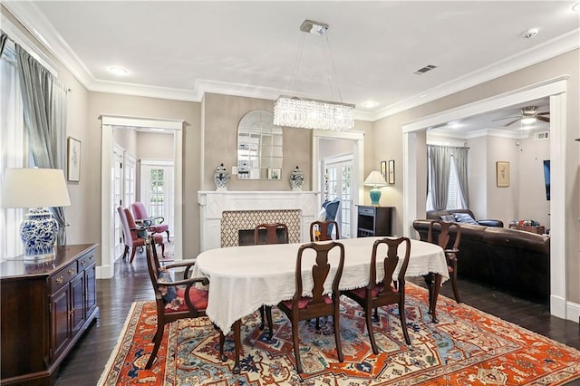 5024 S Claiborne Ave, New Orleans, LA 70125 - dining area with dark wood-style flooring, a ceiling fan, a tiled fireplace, ornamental molding, and recessed lighting