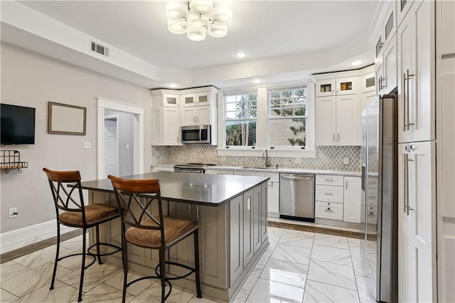 5024 S Claiborne Ave, New Orleans, LA 70125 - kitchen featuring appliances with stainless steel finishes, light marble finish floors, decorative backsplash, a chandelier, and a breakfast bar area
