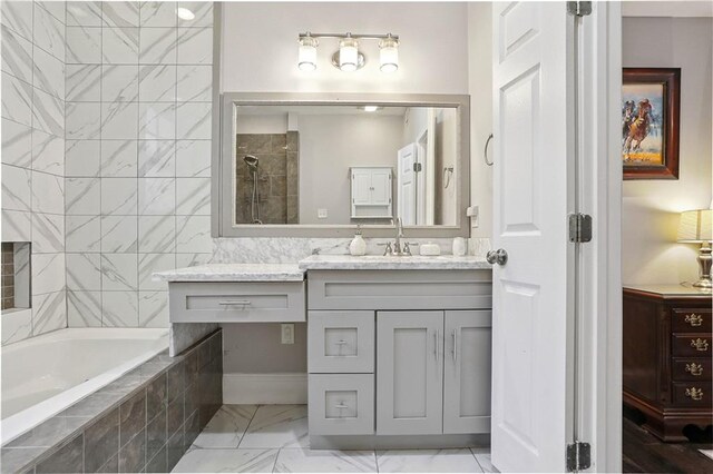 5024 S Claiborne Ave, New Orleans, LA 70125 - bathroom with vanity, marble look tiles, a garden tub, and tiled shower