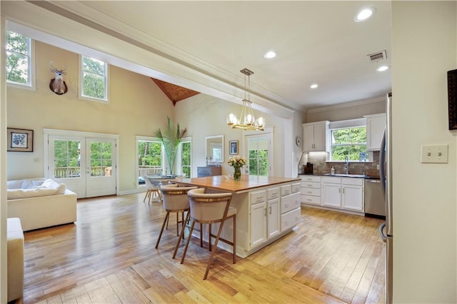 921 Carriage Way, Baton Rouge, LA 70808 - kitchen featuring white cabinets, light wood-type flooring, a kitchen breakfast bar, a kitchen island, and a chandelier
