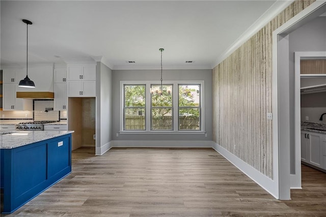163 S 7th St, Ponchatoula, LA 70454 - kitchen with white cabinets, light stone counters, light wood finished floors, crown molding, and pendant lighting