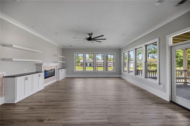 163 S 7th St, Ponchatoula, LA 70454 - unfurnished living room with plenty of natural light, a glass covered fireplace, crown molding, a ceiling fan, and dark wood-style flooring