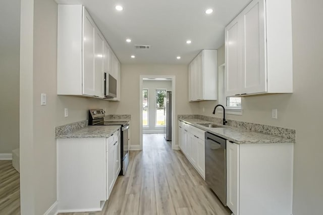 217 Chess Dr, Slidell, LA 70458 - kitchen with appliances with stainless steel finishes, light wood-style floors, recessed lighting, white cabinetry, and light stone counters