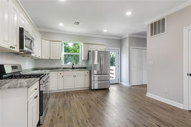 2626 N Dorgenois St, New Orleans, LA 70117 - kitchen featuring appliances with stainless steel finishes, crown molding, white cabinets, light wood-style floors, and recessed lighting