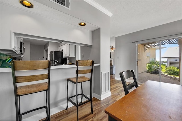 109 Topsl Dr Unit 109, Mandeville, LA 70448 - kitchen featuring wood finished floors, a peninsula, freestanding refrigerator, a textured ceiling, and a kitchen breakfast bar