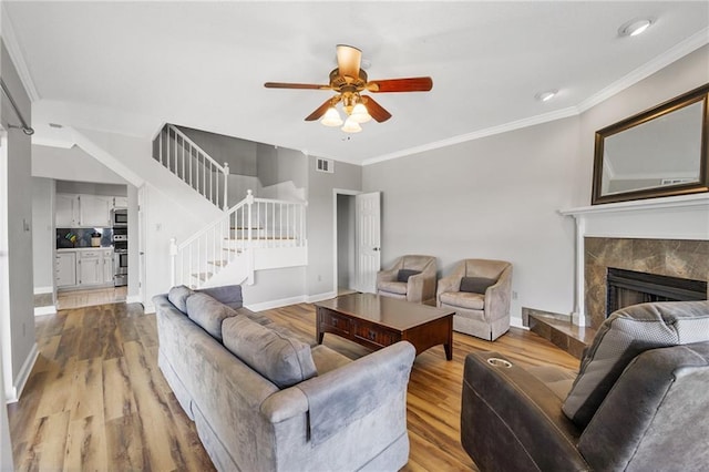 109 Topsl Dr Unit 109, Mandeville, LA 70448 - living area featuring stairs, wood finished floors, ceiling fan, a fireplace, and crown molding