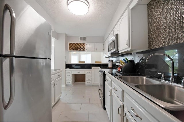 109 Topsl Dr Unit 109, Mandeville, LA 70448 - kitchen with appliances with stainless steel finishes, white cabinetry, a textured ceiling, light marble finish floors, and decorative backsplash