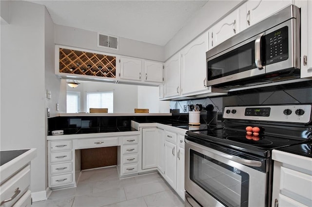 109 Topsl Dr Unit 109, Mandeville, LA 70448 - kitchen featuring stainless steel appliances, white cabinetry, backsplash, dark countertops, and a peninsula