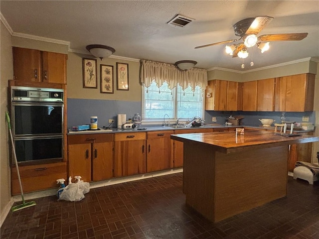 19343 9th Ave, Covington, LA 70433 - kitchen with brown cabinets, a ceiling fan, ornamental molding, a center island, and butcher block counters