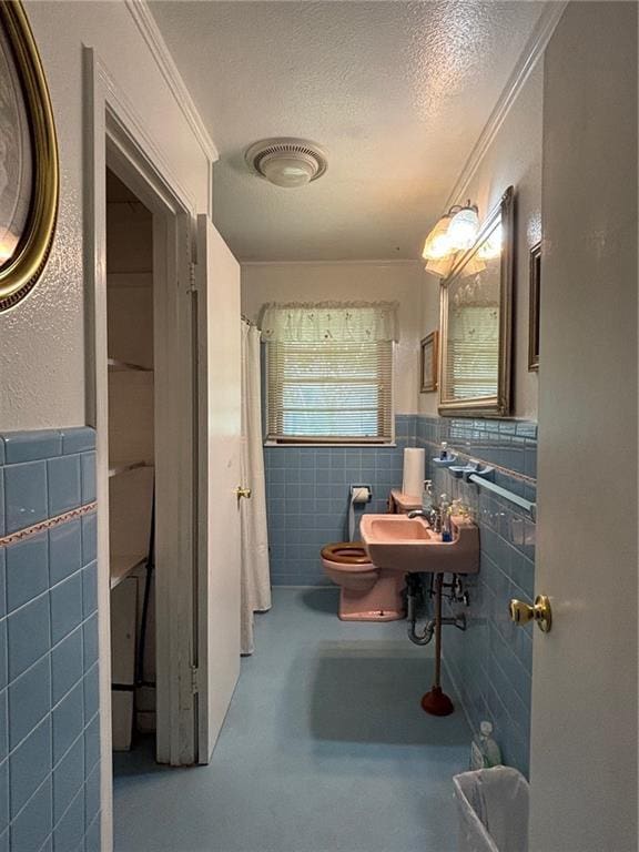 19343 9th Ave, Covington, LA 70433 - bathroom featuring tile walls, concrete floors, a shower with curtain, a textured ceiling, and a wainscoted wall