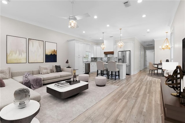 2028 Charles Dr, Chalmette, LA 70043 - living area featuring light wood-type flooring, a ceiling fan, recessed lighting, crown molding, and a chandelier
