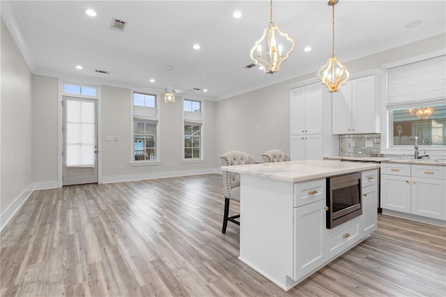 2028 Charles Dr, Chalmette, LA 70043 - kitchen featuring stainless steel microwave, open floor plan, a breakfast bar, recessed lighting, and a chandelier