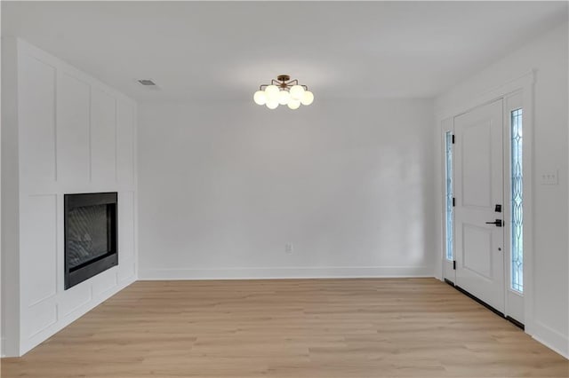 1208 Madison St, Metairie, LA 70001 - entryway with light wood-style flooring, a fireplace, and a chandelier