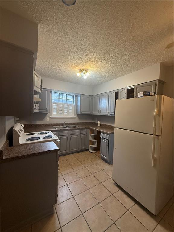 3112 Phoenix St Unit D, Kenner, LA 70065 - kitchen with white appliances, dark countertops, a textured ceiling, gray cabinetry, and light tile patterned flooring
