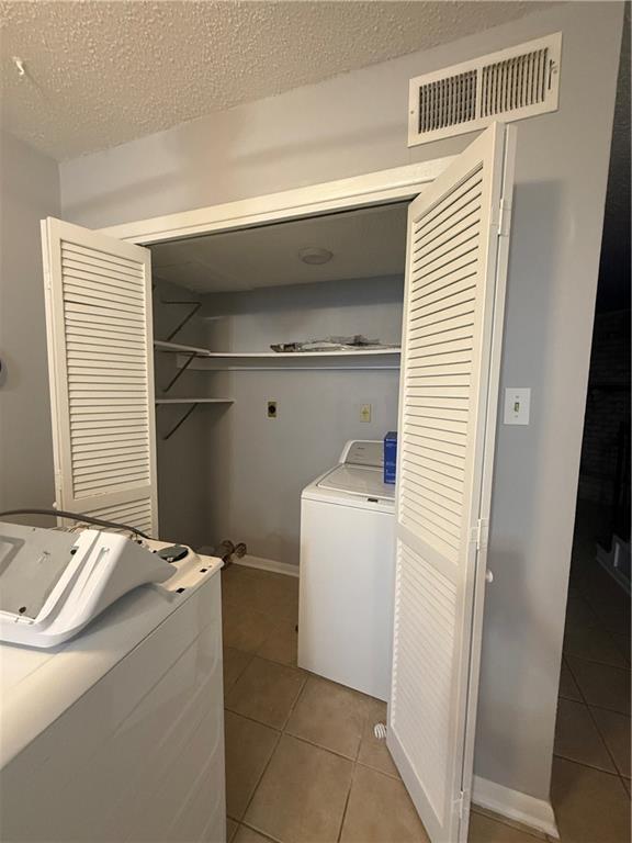 3112 Phoenix St Unit D, Kenner, LA 70065 - laundry room with light tile patterned floors, washing machine and clothes dryer, and a textured ceiling