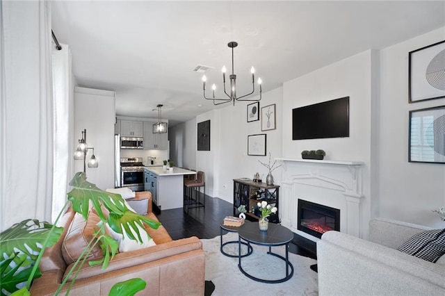 2231 Constance St, New Orleans, LA 70130 - living room with dark wood-type flooring, a chandelier, and a glass covered fireplace