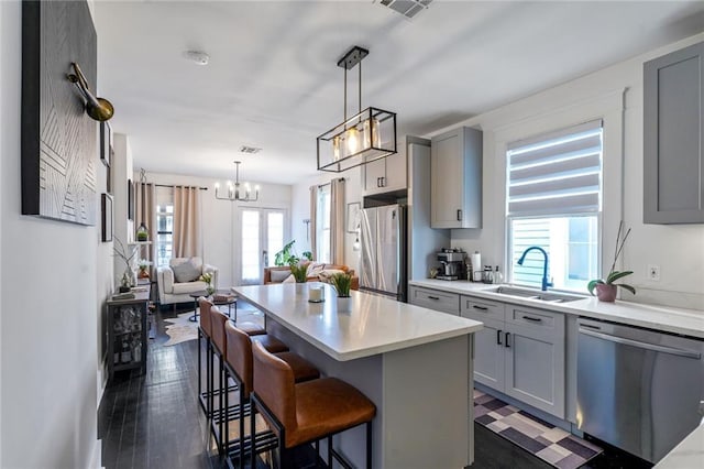 2231 Constance St, New Orleans, LA 70130 - kitchen with stainless steel appliances, gray cabinetry, a chandelier, and healthy amount of natural light