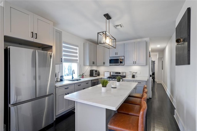 2231 Constance St, New Orleans, LA 70130 - kitchen featuring appliances with stainless steel finishes, a kitchen island, a breakfast bar, pendant lighting, and dark wood finished floors