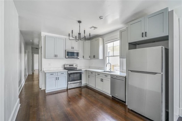 2231 Constance St, New Orleans, LA 70130 - kitchen with stainless steel appliances, a chandelier, light countertops, dark wood finished floors, and decorative light fixtures