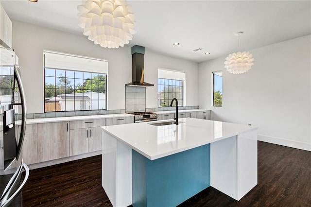 6000 Franklin Ave, New Orleans, LA 70122 - kitchen with wall chimney range hood, stainless steel appliances, dark wood finished floors, light countertops, and a center island with sink