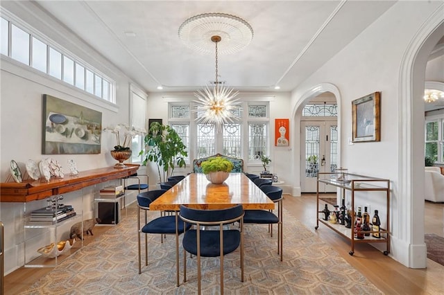 1455 Moss St, New Orleans, LA 70119 - dining space with french doors, wood finished floors, arched walkways, a raised ceiling, and a chandelier