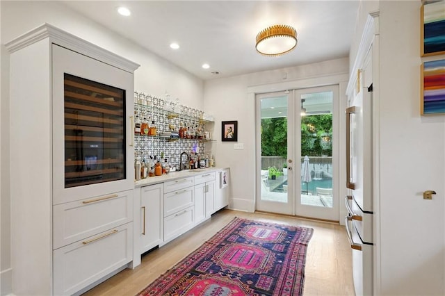 1455 Moss St, New Orleans, LA 70119 - indoor wet bar featuring french doors, decorative backsplash, light wood-style floors, recessed lighting, and freestanding refrigerator