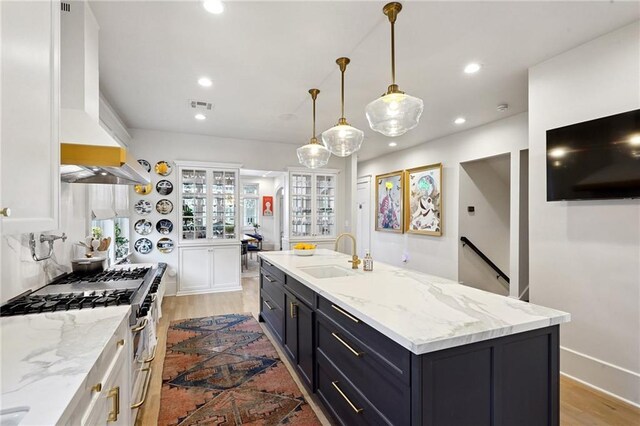 1455 Moss St, New Orleans, LA 70119 - kitchen with stainless steel range with gas cooktop, recessed lighting, an island with sink, premium range hood, and light stone countertops