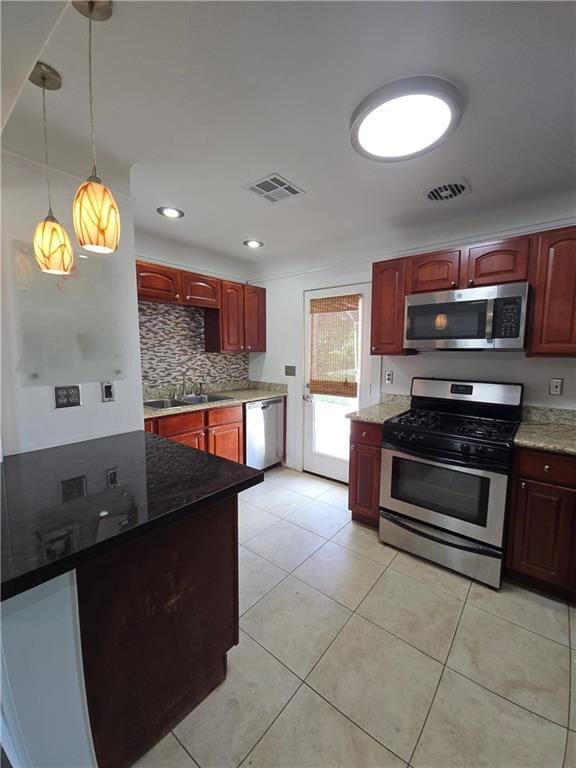 557 Grove Ave, Harahan, LA 70123 - kitchen featuring appliances with stainless steel finishes, dark brown cabinets, tasteful backsplash, light tile patterned floors, and dark stone countertops