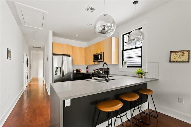 1039-41 Poland Ave, New Orleans, LA 70117 - kitchen featuring appliances with stainless steel finishes, a peninsula, light brown cabinets, and dark wood-style flooring