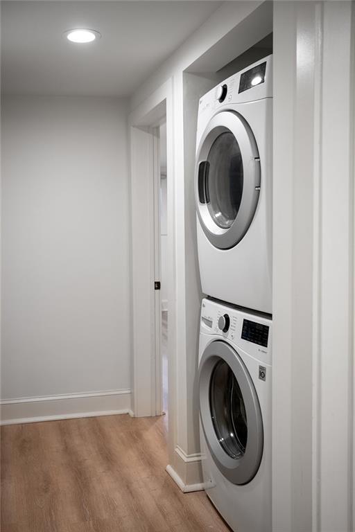 1039-41 Poland Ave, New Orleans, LA 70117 - laundry room with stacked washing machine and dryer, wood finished floors, and recessed lighting