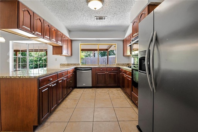905 Rue Rochelle, Slidell, LA 70458 - kitchen with appliances with stainless steel finishes, light stone counters, light tile patterned flooring, a textured ceiling, and a peninsula