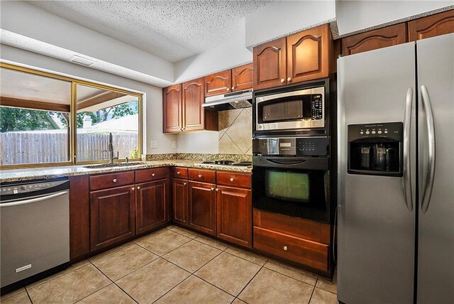 905 Rue Rochelle, Slidell, LA 70458 - kitchen with stainless steel appliances, under cabinet range hood, a textured ceiling, light tile patterned floors, and light stone countertops