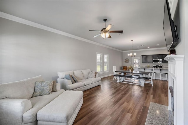 42016 Wood Ave, Ponchatoula, LA 70454 - living area featuring a ceiling fan, crown molding, dark wood-style flooring, a chandelier, and a fireplace with flush hearth