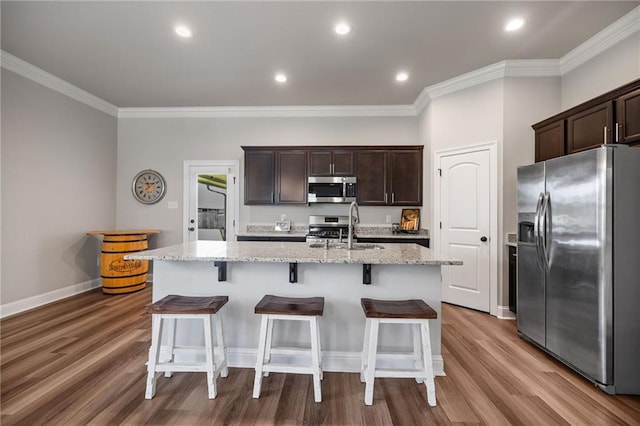 42016 Wood Ave, Ponchatoula, LA 70454 - kitchen with stainless steel appliances, wood finished floors, dark brown cabinetry, crown molding, and an island with sink