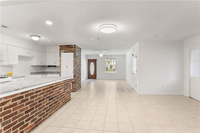 4720 Sheridan Ave, Metairie, LA 70002 - kitchen with brick wall, a textured ceiling, white cabinetry, open floor plan, and a ceiling fan