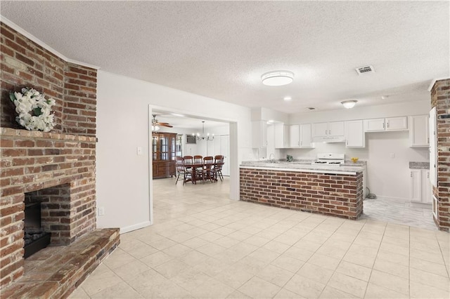 4720 Sheridan Ave, Metairie, LA 70002 - kitchen with a brick fireplace, stove, light countertops, white cabinetry, and light tile patterned floors