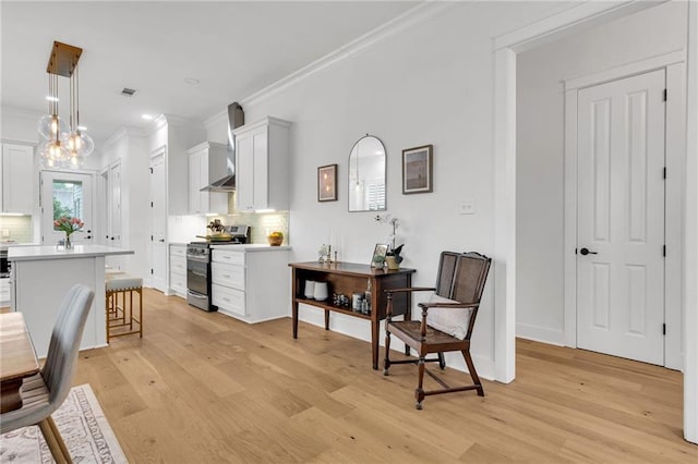5756 Warrington Dr, New Orleans, LA 70122 - kitchen featuring stainless steel range with electric cooktop, crown molding, light wood-type flooring, decorative backsplash, and a kitchen breakfast bar