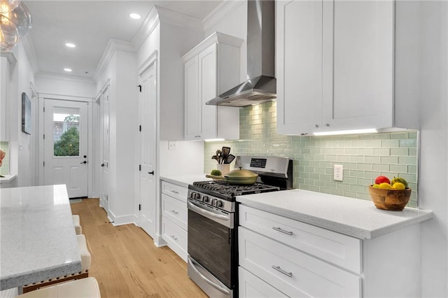 5756 Warrington Dr, New Orleans, LA 70122 - kitchen with gas stove, wall chimney range hood, crown molding, light wood finished floors, and white cabinets
