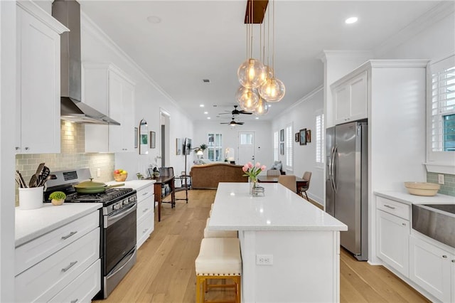5756 Warrington Dr, New Orleans, LA 70122 - kitchen featuring stainless steel appliances, wall chimney exhaust hood, a kitchen island, open floor plan, and a ceiling fan