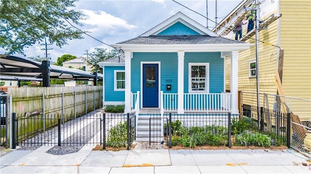 1323 S Rampart St, New Orleans, LA 70113 - shotgun-style home featuring a porch, a shingled roof, a fenced front yard, and a gate