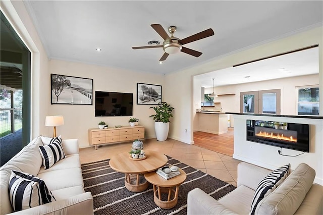 2549 Villere St, Mandeville, LA 70448 - living area featuring light tile patterned floors, healthy amount of natural light, ornamental molding, ceiling fan, and a glass covered fireplace