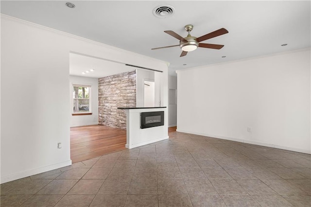 2549 Villere St, Mandeville, LA 70448 - unfurnished living room featuring ceiling fan, crown molding, a glass covered fireplace, and tile patterned floors