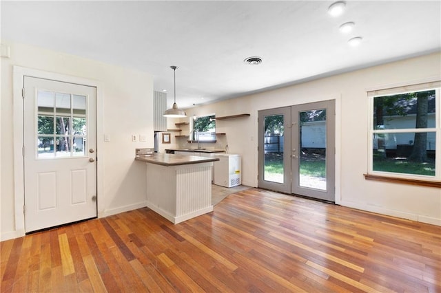 2549 Villere St, Mandeville, LA 70448 - kitchen featuring a peninsula, light wood finished floors, french doors, pendant lighting, and open shelves