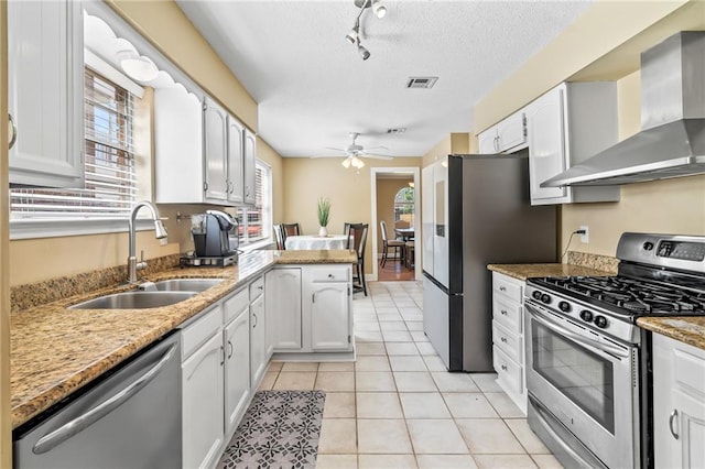3540 Silver Maple Ct, New Orleans, LA 70131 - kitchen featuring stainless steel appliances, wall chimney exhaust hood, a peninsula, ceiling fan, and a textured ceiling