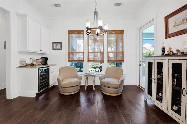 225 Chateau Papillon, Mandeville, LA 70471 - sitting room featuring wine cooler, a bar, a chandelier, dark wood-style flooring, and ornamental molding