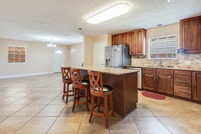122 Warwick St, La Place, LA 70068 - kitchen with refrigerator with ice dispenser, dishwasher, backsplash, a kitchen breakfast bar, and a textured ceiling