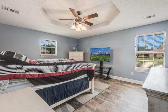 122 Warwick St, La Place, LA 70068 - bedroom featuring a textured ceiling, a tray ceiling, wood finished floors, and a ceiling fan